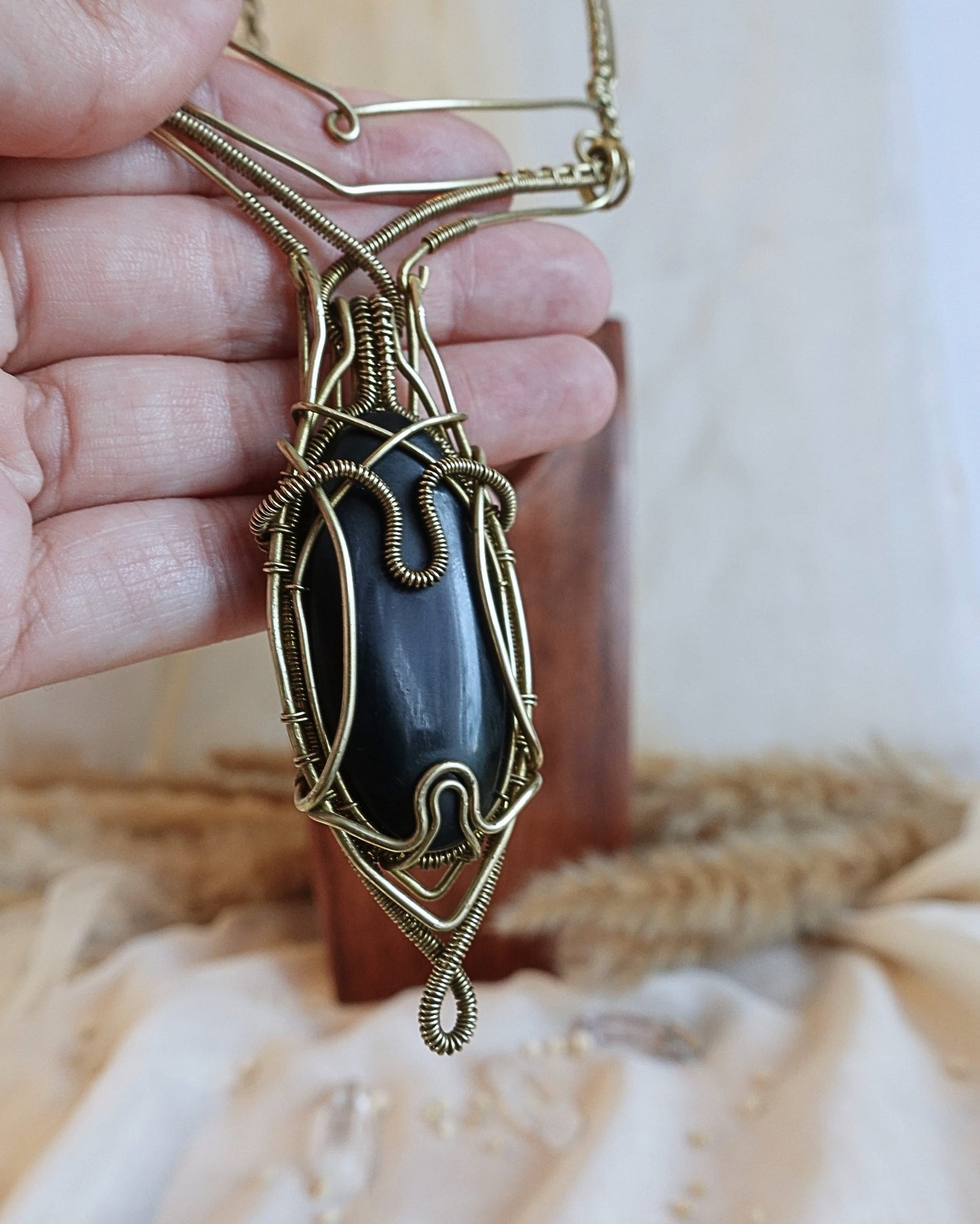 Side view of Black Onyx VÏ wirewrap pendant on brass chain