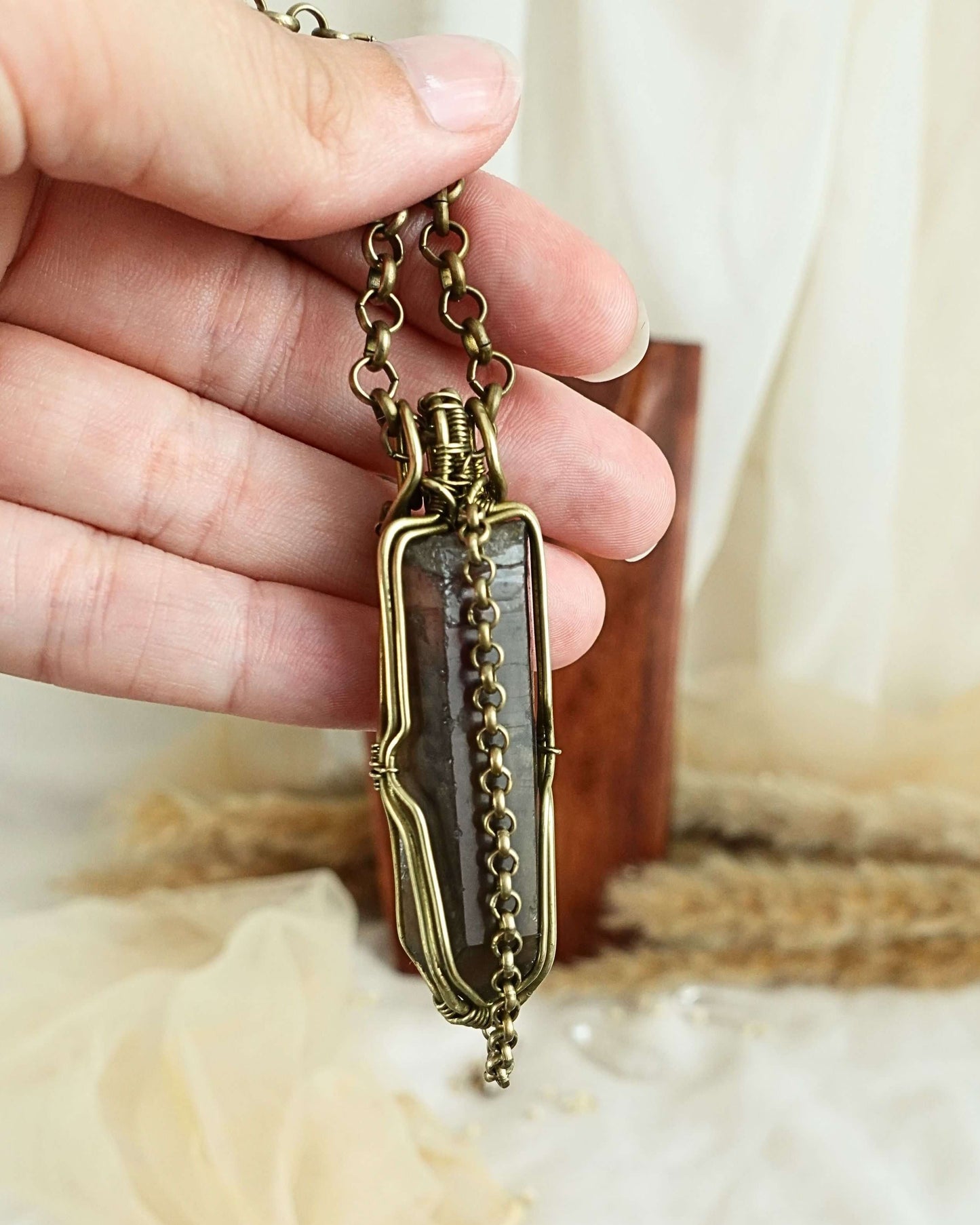 Side view of black quartz pendulum wirewrap pendant on brass chain