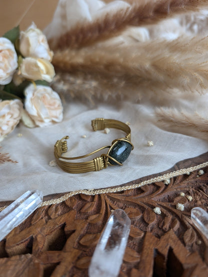Detail of brass wirework holding the dark jade stone