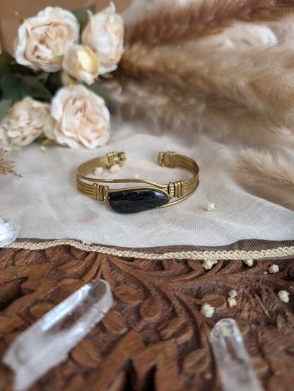 Side view of rainbow obsidian bracelet in adjustable brass wire