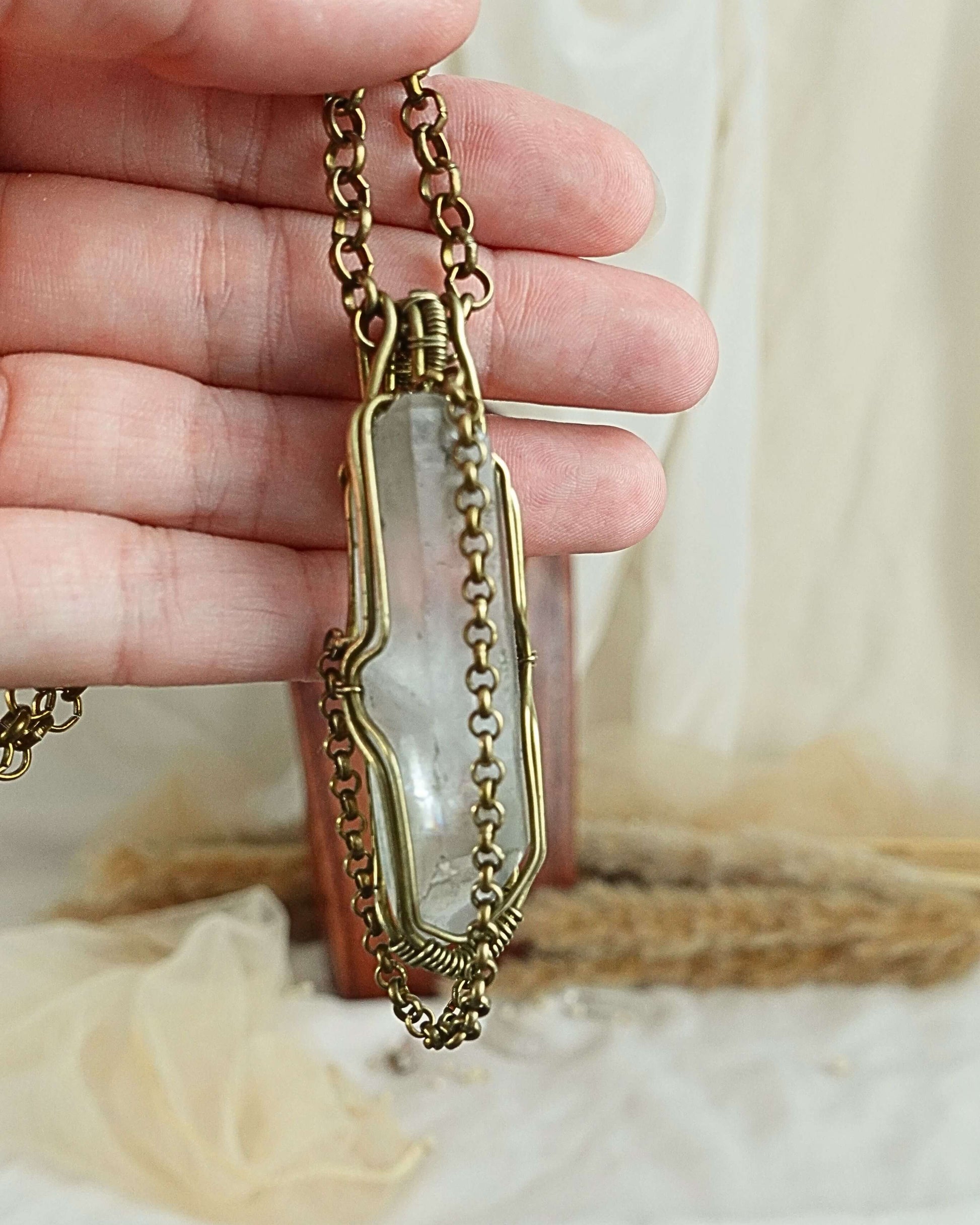 Side view of clear quartz pendulum wirewrap pendant on brass chain