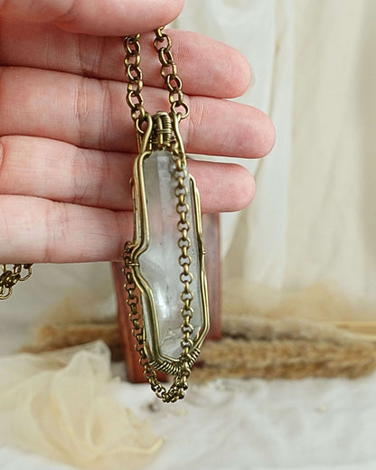 Side view of clear quartz pendulum wirewrap pendant on brass chain